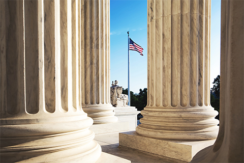 Image of the US Flag amidst government building columns