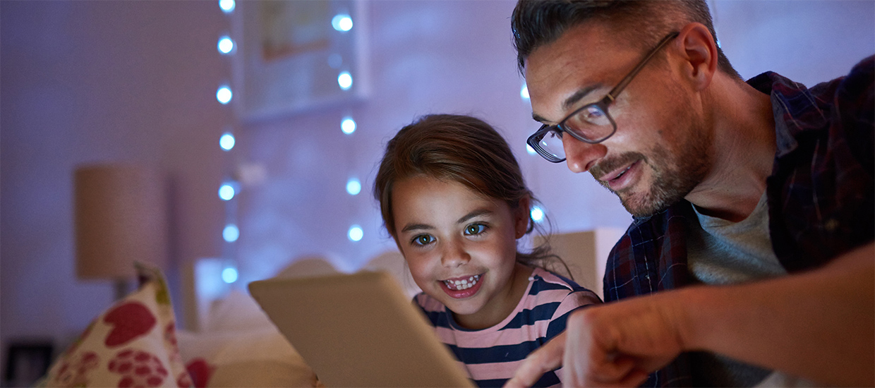 Image of a father reading to his child from an IPad