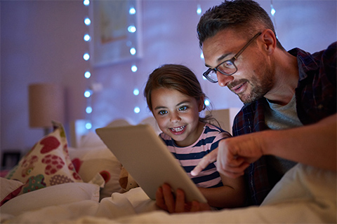 Image of a father reading to his child from an IPad