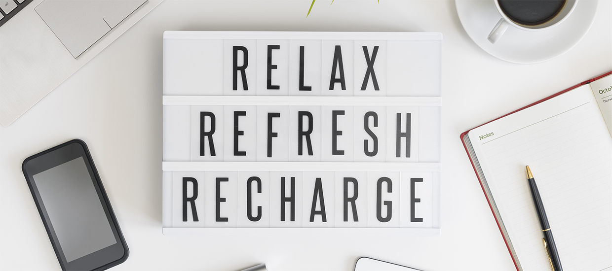 Image of a sign reading "Relax, Refresh, Recharge" atop a workbench