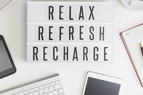 Image of a sign reading "Relax, Refresh, Recharge" atop a workbench